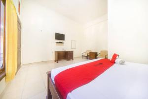 Un dormitorio con una cama con una manta roja. en RedDoorz near Nusa Cendana University en Kupang