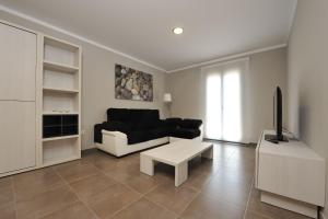 a living room with a black couch and a tv at Aparthotel Meseguer in Alcañiz