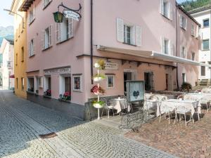 una calle con mesas y sillas frente a un edificio rosa en Hotel Centrale, Typically Swiss, en Poschiavo