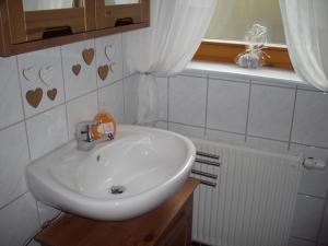 ein weißes Waschbecken im Bad mit Herzen an der Wand in der Unterkunft Ferienwohnung Klatt-Gallus in Meißenheim