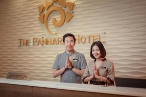 a man and woman standing behind a counter with their hands up at The Pannarai Hotel in Udon Thani