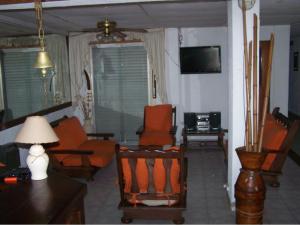 a living room with orange chairs and a television at Apart Hotel Monaco in Santa Teresita