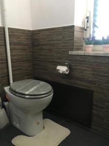 uma casa de banho com um WC com um assento cinzento e uma janela em Mondello Room em Mondello