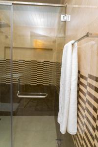 a bathroom with two white towels hanging on a shower at MRD Beach Hotel in Trincomalee
