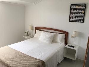 a bedroom with a large bed with white sheets and pillows at Pension Rosalia de Castro in Foz