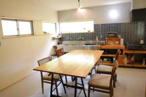 cocina con mesa de madera y sillas en 猫と図書館のある宿 草地家 Kusachike en Minamiawaji