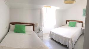 two beds in a white room with green pillows at Pension Rosalia de Castro in Foz +11 photos