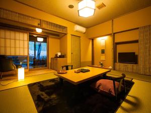 a living room with a table and a television at Kurokawa-So in Minamioguni