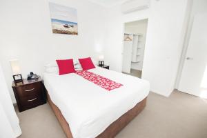 a bedroom with a large white bed with red pillows at Curtis Central Apartments in Gladstone