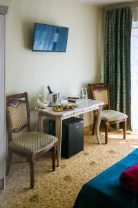 a living room with a table, chairs and a tv at Grand Rose SPA Hotel in Kuressaare