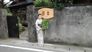 Una donna in piedi accanto a un muro con un mucchio di verdoni di Guesthouse Sakichi a Beppu
