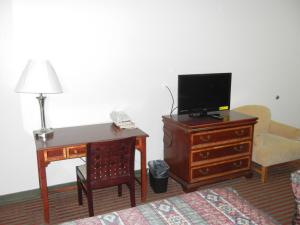 um quarto com uma secretária e uma televisão numa cómoda em The Surrey Inn em Caldwell