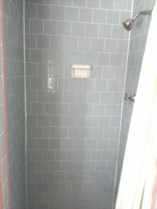 ducha con azulejos azules y cortina de ducha en Beachtree Motel en Galveston