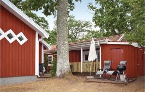 a red house with a tree and a grill at Awesome Home In Lttorp With Kitchen in Löttorp