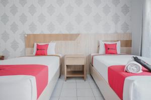 - 2 lits dans une chambre avec des draps rouges et blancs dans l'établissement RedDoorz Syariah near RSUD Kolonel Abundjani Bangko, à Bangko