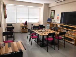 a dining room with tables and chairs and a flat screen tv at Hostel Mallika in Hiroshima