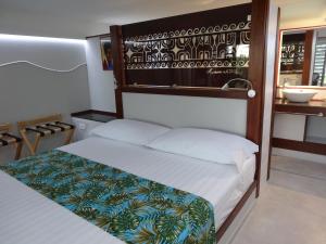 a bedroom with a bed with a wooden headboard at Pension Tiputa Lodge Rangiroa in Tiputa