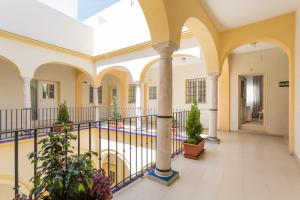un couloir vide d'un bâtiment avec colonnes et plantes dans l'établissement Apartamentos Alberto Lista 9, à Séville