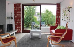 salon z czerwoną kanapą i kominkiem w obiekcie Pet Friendly Home In Nieuwvliet-bad With Kitchen w mieście Nieuwvliet-Bad