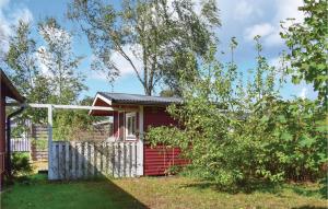 a red house with a white fence in a yard at Two-Bedroom Holiday Home In Skummeslov in SkummeslÃ¶v