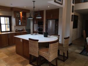 una cocina con una isla con fregadero y sillas en De Zalze Luxury Lodge, en Stellenbosch