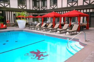 a large swimming pool with chairs and red umbrellas at The Cheshire in Saint Louis