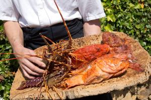 a person holding a plate with a bunch of lobster at La Ferme D'Augustin in Saint-Tropez