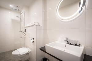 a white bathroom with a sink and a mirror at Hotel New Kit in Amsterdam