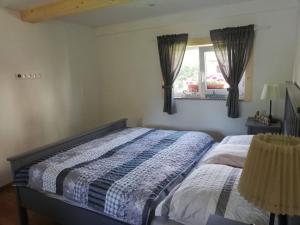 a bedroom with a bed and a window with curtains at Domček pri vode in Mlynčeky