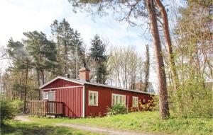 a red cabin in the woods with a tree at Stunning Home In Simrishamn With Kitchen in Simrishamn