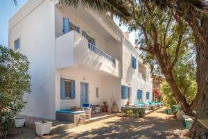 a large white building with blue windows and trees at Astra Studios in Astypalaia
