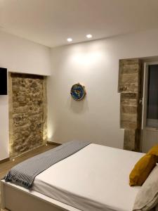 1 dormitorio con 1 cama y reloj en la pared en Nesh House, en Siracusa