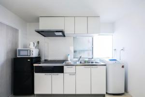 a white kitchen with a sink and a refrigerator at Seto Building in Osaka