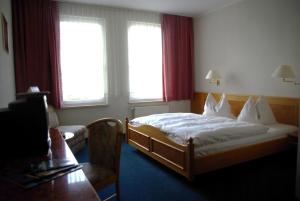 ein Schlafzimmer mit einem Bett, einem Sofa und Fenstern in der Unterkunft Hotel Güldene Gabel in Unterwellenborn