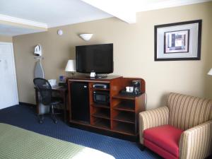 a hotel room with a tv and a desk and chairs at Inn at Bayshore in San Mateo
