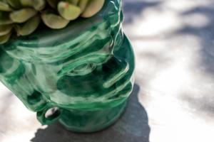 a green glass vase with a bunch of flowers in it at Hotel Mignon Meublè in Sorrento