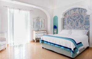 Schlafzimmer mit einem Bett mit einem blauen und weißen Kopfteil in der Unterkunft Villa Boheme Exclusive Luxury Suites in Positano