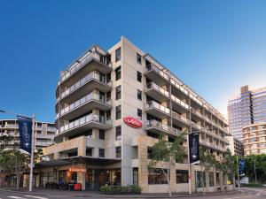 ein großes graues Gebäude mit einem roten Schild darauf in der Unterkunft Adina Apartment Hotel Sydney, Darling Harbour in Sydney
