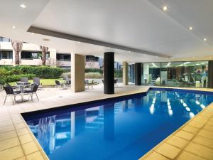 an indoor swimming pool with blue water in a house at Adina Apartment Hotel Sydney, Darling Harbour in Sydney