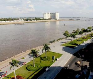 a view of a river with palm trees and a building at Velkommen Guesthouse Phnom Penh in Phnom Penh