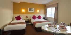 a hotel room with two beds and two tables at Eviston House Hotel in Killarney