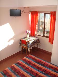 a room with a table and a window with a vase of flowers at Hotel Frontera in La Quiaca