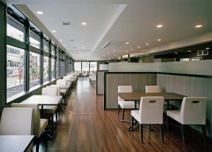 a dining room with tables and white chairs at Hotel New Amami in Amami