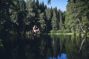 a man sitting on a rock in the middle of a lake at Blickinsfreie - Cabin in Schöneck