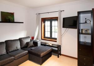 uma sala de estar com um sofá e uma televisão em A Ilha do Lindo Vale no Porto