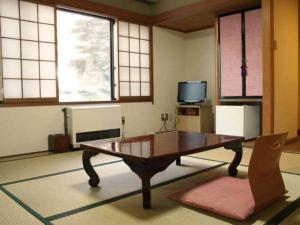 a living room with a coffee table and a tv at Yakushi no Yu Yumotokan in Kusatsu
