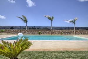 a swimming pool with palm trees in the background at Tenuta De Masi by LoveSud in Corsano +45 photos