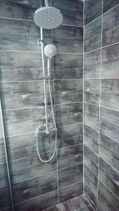 eine Dusche in einem Badezimmer mit einer Holzwand in der Unterkunft BBS Residence in Cluj-Napoca
