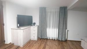 ein Zimmer mit einem Fernseher auf einer Kommode mit einem Vorhang in der Unterkunft BBS Residence in Cluj-Napoca + 48 Fotos