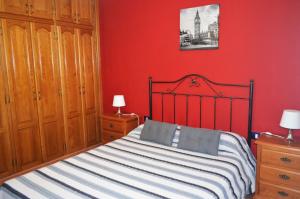 1 dormitorio con cama y pared roja en Casa de Campo Hiurma, en Triquivijate